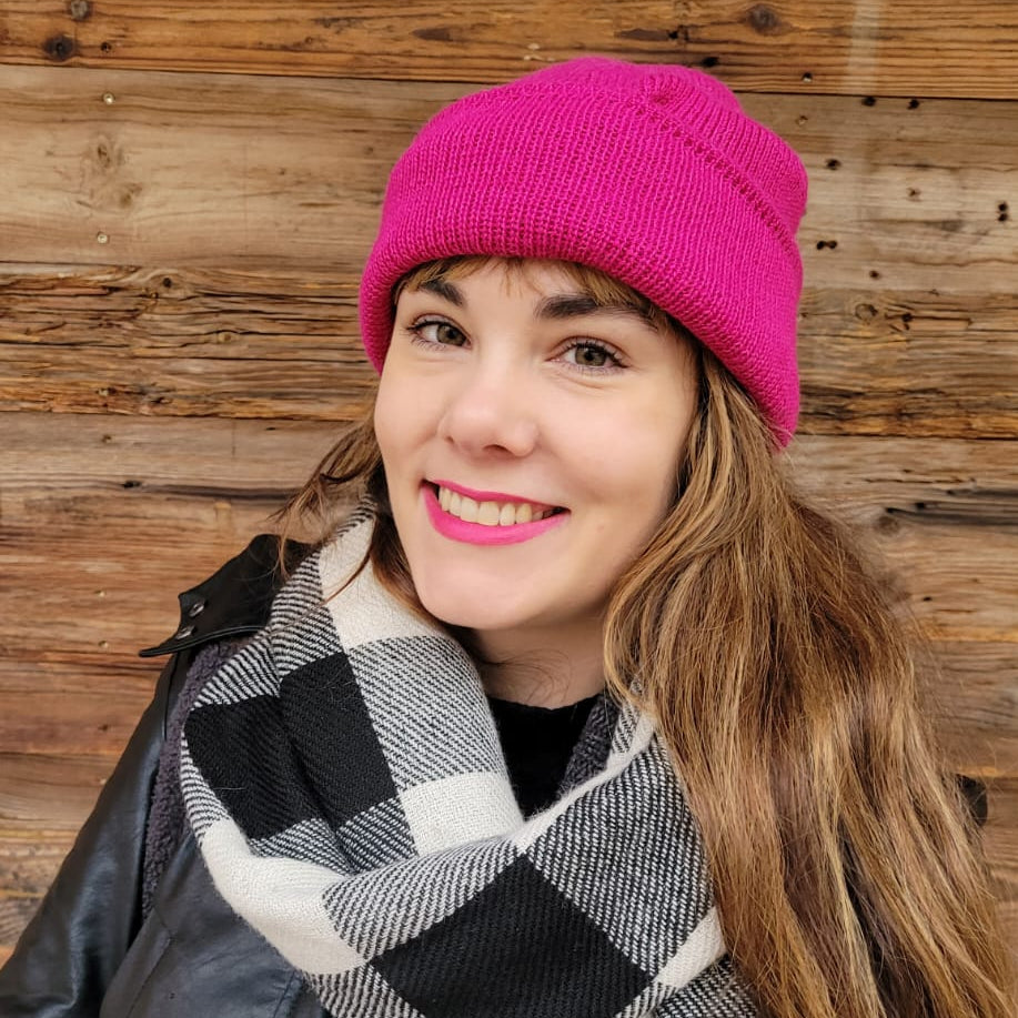 Woman wearing a 100% baby alpaka pink beanie from Bolivia  and black and white scarf handwoven  in Bolivia
