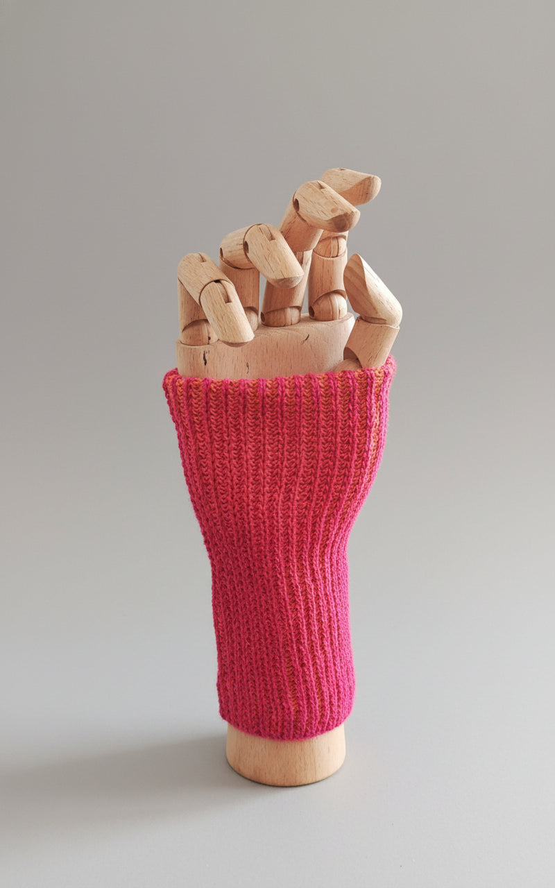 Pink knitted wrist warmer handmade with 100% Baby Alpaka Wool in Bolivia on a wooden mannequin hand against a white background